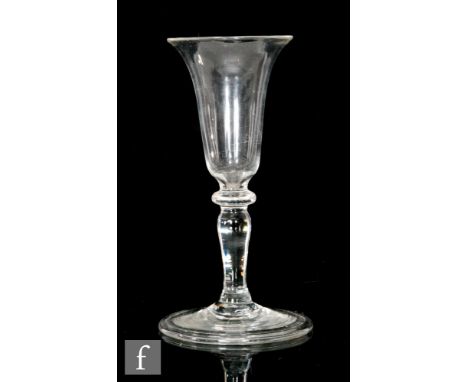 An 18th Century Gin glass circa 1740, the narrow bell form bowl above a flattened knop and slender inverted baluster stem wit