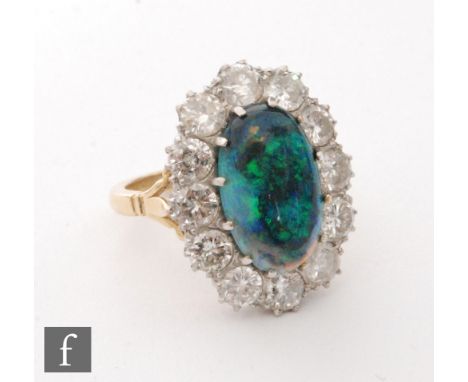 An 18ct black opal and diamond cluster ring, central oval opal, length 15mm, within a twelve stone brilliant cut diamond surr