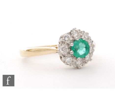 An 18ct hallmarked emerald and diamond cluster ring, central circular emerald within an eight stone brilliant cut diamond sur