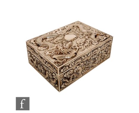 An early 20th Century Chinese silver box decorated with embossed three clawed dragons among clouds to all sides, length 17cm,