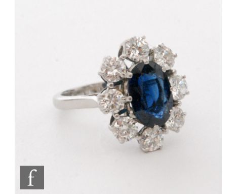 A platinum set sapphire and diamond cluster ring, central oval sapphire, length 10mm, within an eight stone brilliant cut dia