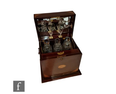 A 19th inlaid mahogany tantalus, decorated with batwing spandrels and roundels, the hinged mirror backed cover, revealing fit