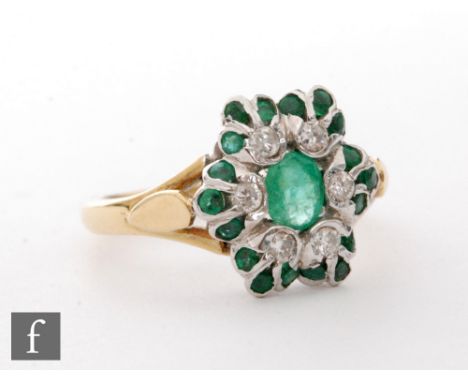 An 18ct hallmarked emerald and diamond cluster ring, central oval emerald within a six stone diamond surround and further eig