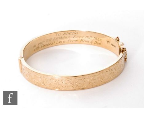 A 9ct hallmarked hinged bangle with foliate engraving to front and presentation engraving to interior, weight 16.6g, Chester 