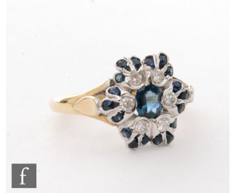 An 18ct hallmarked sapphire and diamond cluster ring, central oval sapphire within a six stone diamond surround and further e