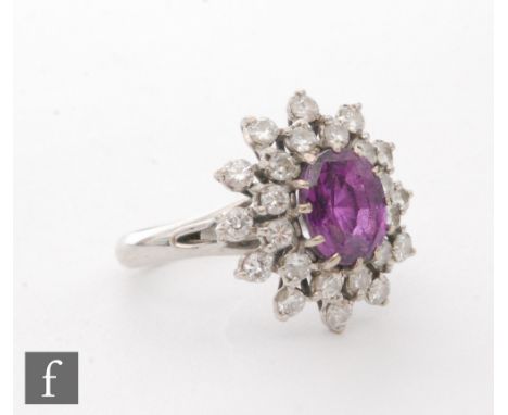 An 18ct white gold ruby and diamond cluster ring, central oval ruby, length 8mm, within a double border of individually set d