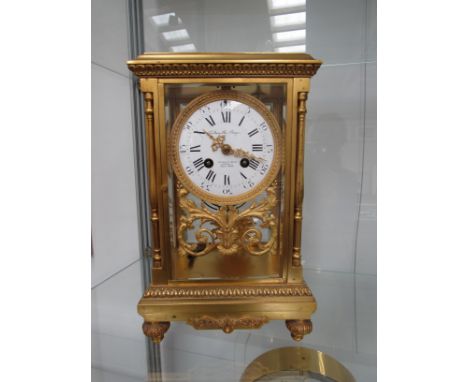 A 19th Century French gilt brass four glass mantel clock, the enamelled Roman dial with pierced gilt hands, retailed by Golds