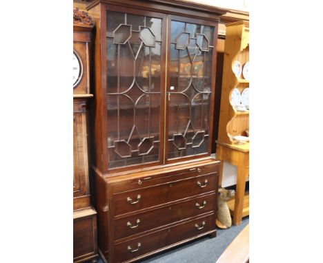 Edwardian mahogany astragal glazed two door bookcase above three drawer chest raised on bracket supports.