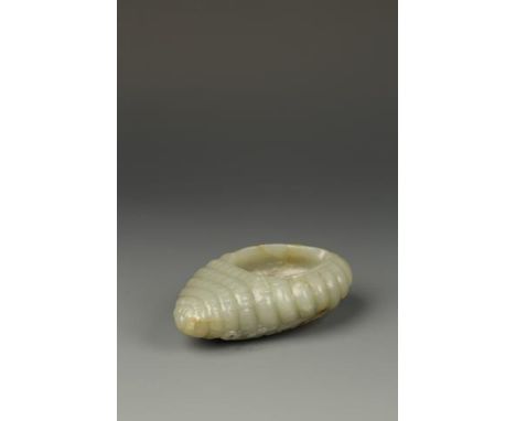 A CHINESE CELADON JADE CONCH SHELL WASHER of asymmetric form, the underside carved with waves, the stone with some russet and