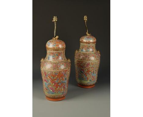 A PAIR OF CHINESE FAMILLE ROSE CORAL-GROUND COVERED VASES decorated with panels of flowers, birds and insects on a foliate gr