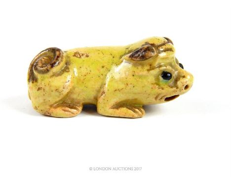 A late 16th / early 17th century Ming dynasty ceramic netsuke in the form of a crouching pig, Length: 5 cm.