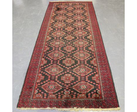 An Afghan wide runner, mid/late 20th century, the charcoal field with columns of stepped guls, within a banded border, 296cm 