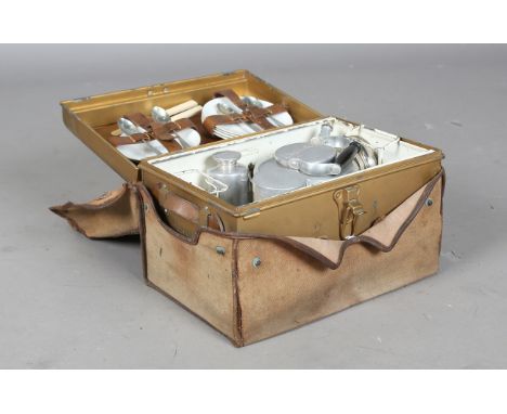 An early 20th century 'Garrison' picnic hamper with hinged gold coloured metal box and outer canvas case, enclosing an arrang