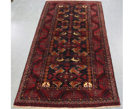 A Mashad Beluche rug, late 20th century, the charcoal field with overall birds and guls, within a claret border, 240cm x 130c