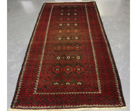 A Beluche rug, Afghan/Persian borders, mid-20th century, the charcoal field with overall horizontal bands of flowerheads, wit