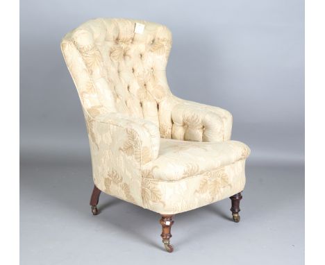 A late Victorian armchair, the substantial buttoned back and seat covered in an Art Nouveau style cotton, on turned walnut le