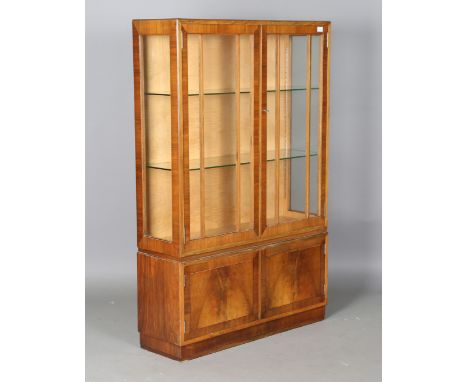 An early 20th century walnut display cabinet by Heals, the interior lined in maple, height 151cm, width 99cm, depth 31cm.Buye