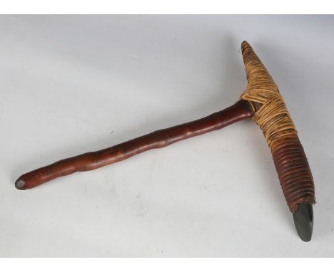 A Papua New Guinea wooden handled grubbing axe with rattan-bound polished stone head, length 47cm. Note: obtained directly by