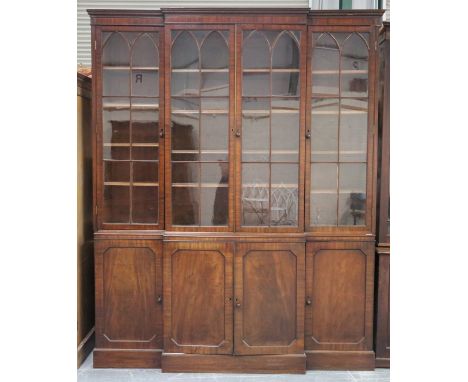 A 19th century mahogany breakfront library bookcase cabinet, the inlaid pediment above lancet glazed doors and panelled cupbo