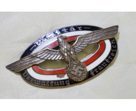 White metal and enamel German Nazi WWII breast badge with central eagle above swastika, the border marked 'Militar Derwaltung