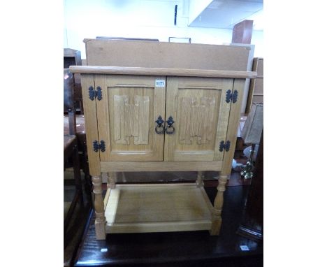 A SMALL LIGHT OAK LINENFOLD TWO DOOR CABINET