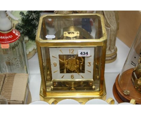 A JAEGER LE COULTRE ATMOS MANTLE CLOCK, in fitted case, with clear glass top and side panels, angled corners and square dial,