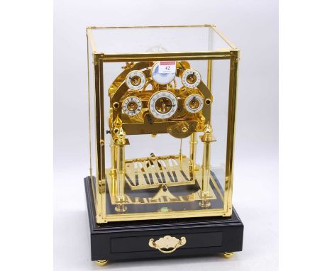 A reproduction brass congreve clock, having six enamel dials and rolling ball movement, housed within a glazed display case, 