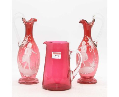A pair of 19th century Mary Gregory style enamel decorated cranberry glass ewers, h.26cm; together with a cranberry glass jug