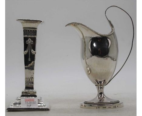 A 19th century silver table candlestick, loaded, h.16.5cm; together with a white metal milk jug, of helmet form, h.19cm 