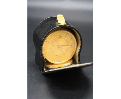 A Jaeger gilt brass cased travelling alarm clock, on oval plinth, h.4.9cm, with original leather travel case 