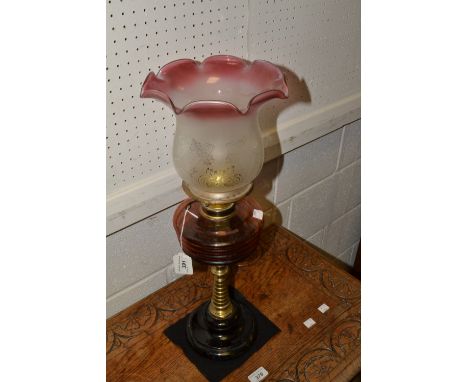 An oil lamp, amber reservoir, knopped brass stem, black base