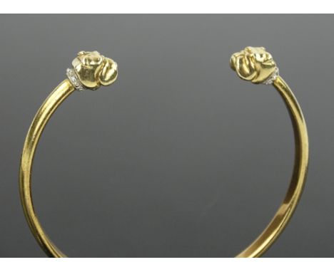 A heavy 9 ct gold bangle with diamond set bulldog head terminals, 31.8 grams