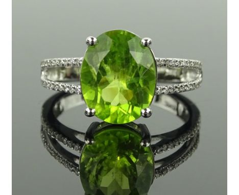 A 14 ct white gold 3.48 carat oval peridot set ring, small diamond set shoulders, size M