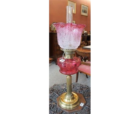 A Late Victorian Brass Corinthian Style Oil Lamp, with cranberry glass reservoir, similar frilly glass shade and glass funnel