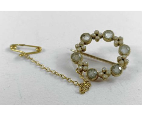 An Edwardian circlet brooch, set with alternating single light blue stones and sets of four seed pearls, marked '15c', 3g gro