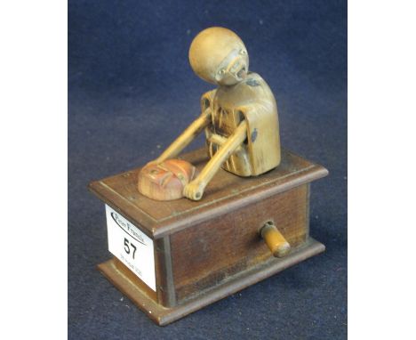 Small automaton type wooden figure on a box, the figure remotely operated with knob to the side pulling a mask towards his fa