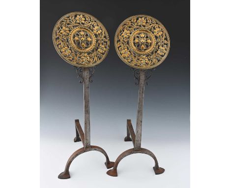A pair of Arts and Crafts brass and wrought iron fire dogs, circa 1900, the pierced foliate roundels cast with cross and foli