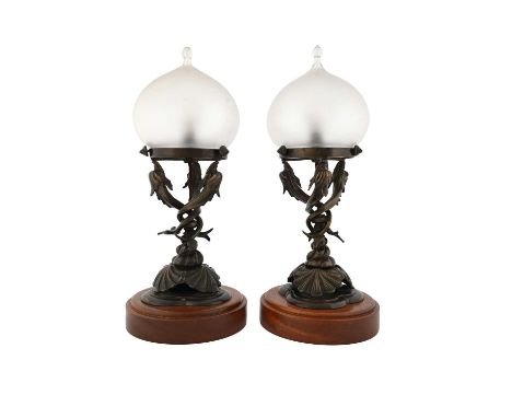 A pair of Arts and Crafts bronze table lamps, modelled in relief as entwined dolphins emerging from a shell encrusted trefoil