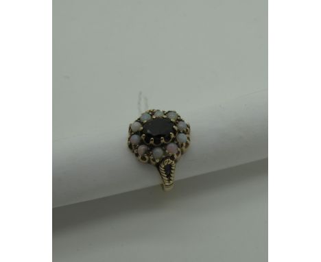 A 9ct Gold Opal And Garnet Cluster Dress Ring, oval claw set to the centre, within border of circular cabochon opals (finger 