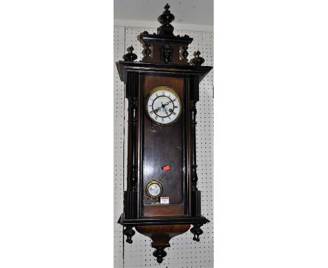 An early 20th century walnut and ebonised Vienna drop trunk wall clock, having pendulum and winding key, height approx 100cm