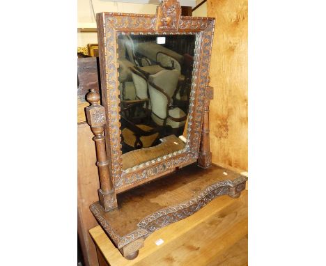 A late Victorian heavily floral carved oak swing dressing mirror, having heraldic lion surmount on serpentine stand, with sin