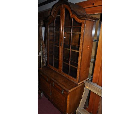 An early 20th century figured walnut and crossbanded dome top display cabinet, having twin glazed upper doors enclosing adjus