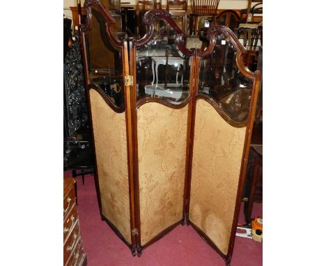 An Edwardian mahogany bevelled glass and floral needlework inset three-fold dressing screen, with acanthus leaf carved detail