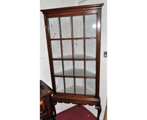 A joined oak freestanding single door glazed corner display cabinet, having brass locking mounts, silk lined interior, and ra