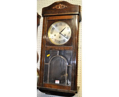 A 1930s beech drop trunk wall clock, having pendulum and winding keys, height 77cm