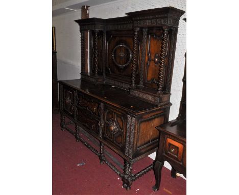 A large early 20th century floral carved and geometric moulded oak panel back sideboard, in the Jacobean taste, with barley t