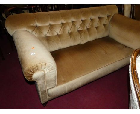 A late Victorian mahogany framed and button back fabric upholstered three-seater sofa, raised on tapering forelegs to castors