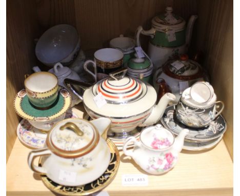 A shelf of collectible ceramics including teapots, cups and saucers etc