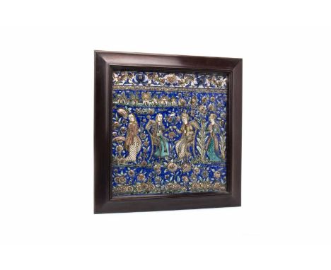 19TH CENTURY QAJAR TILE the rectangular pottery tile, of Persian origin,moulded with two central figures seated and flanked o