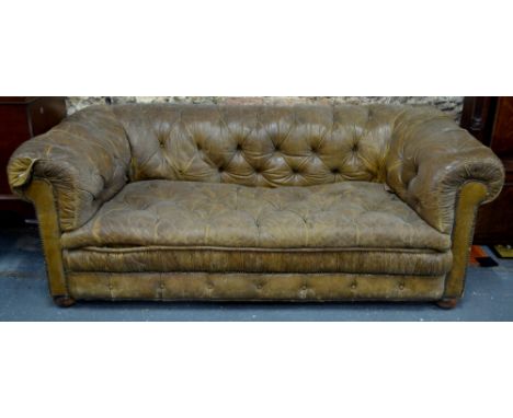 A Victorian/Edwardian buttoned tan/brown leather Chesterfield sofa with brass studded detail, raised on concealed castors, 19